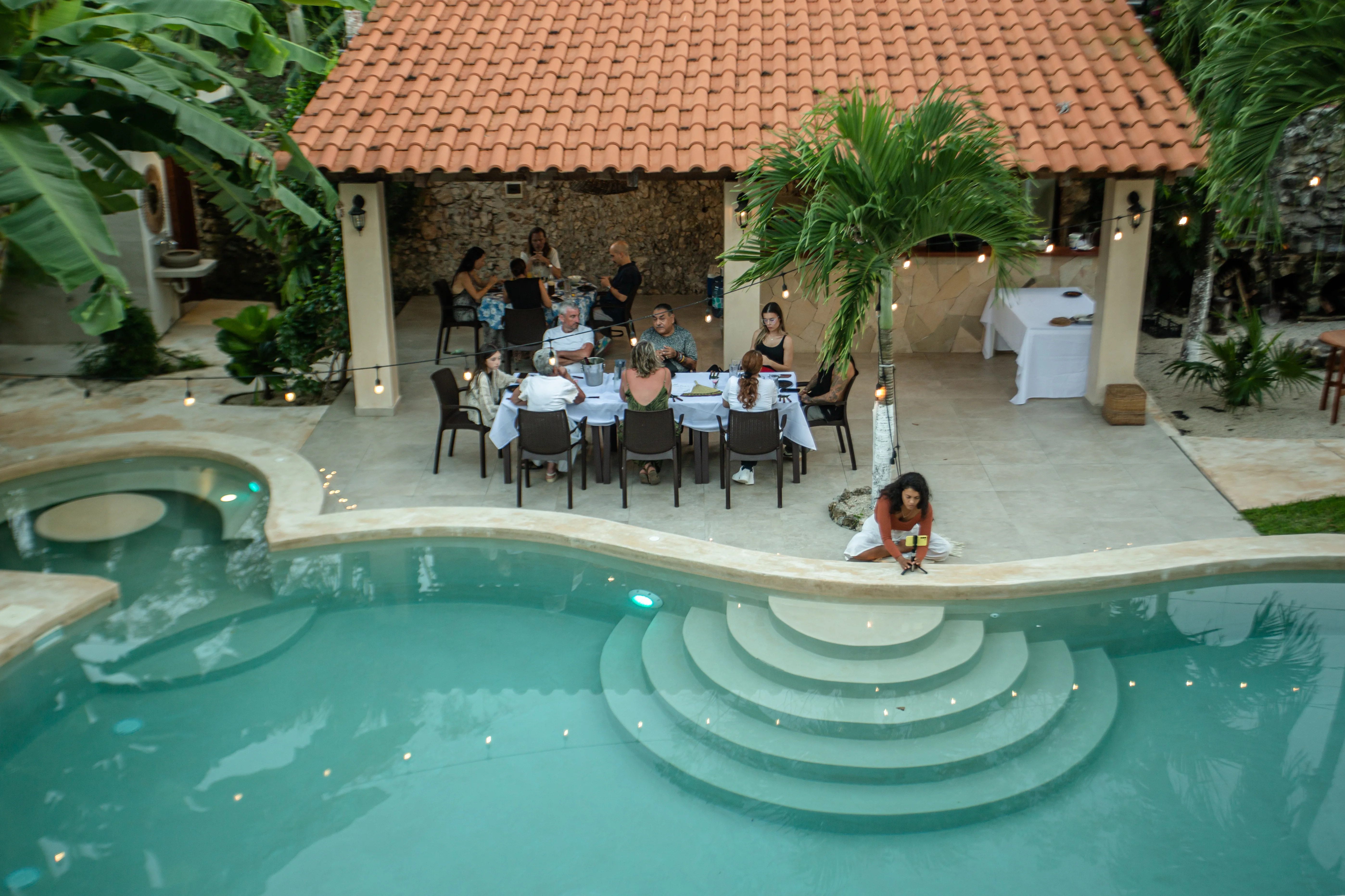 Aerial view of a poolside dinner under the palapa